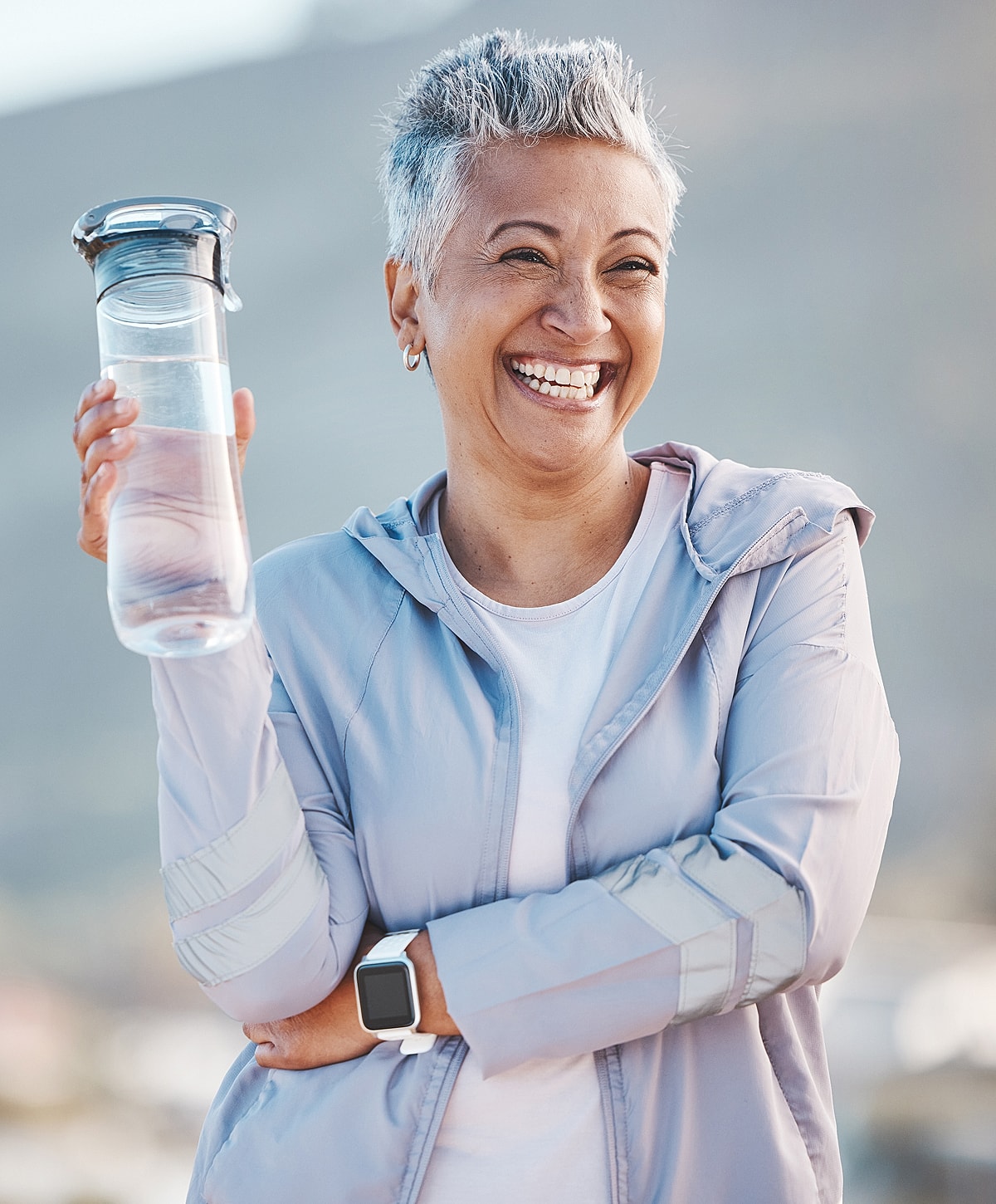 Smiling woman holding a water bottle outdoors.