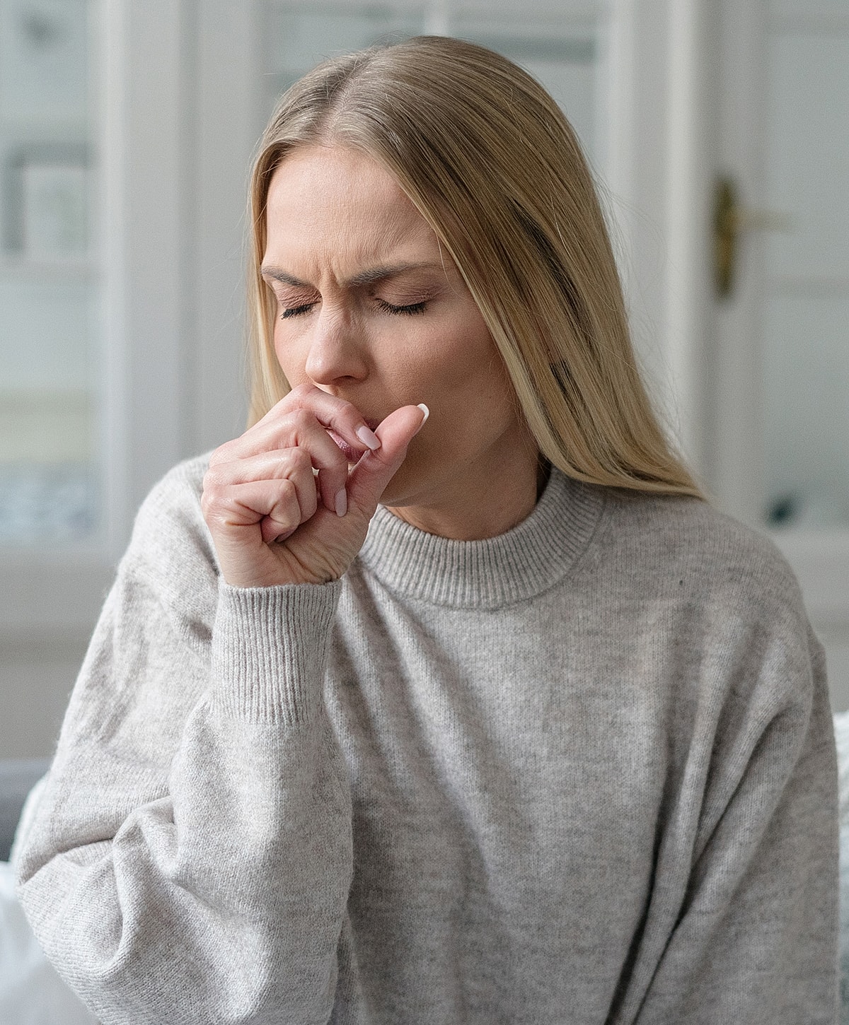 Woman coughing with hand on her mouth.