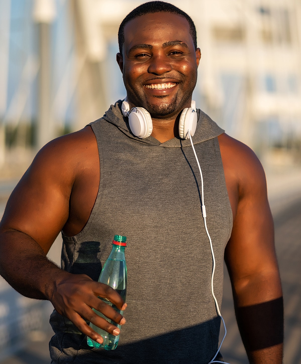 Smiling man holding a water bottle outdoors.