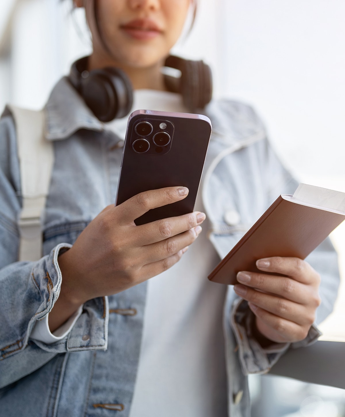 Person holding phone and passport, indoors.