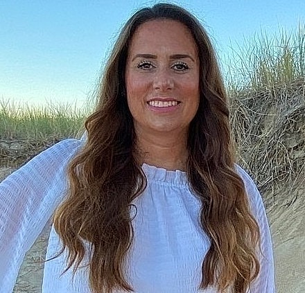 Person standing on beach with grassy background.