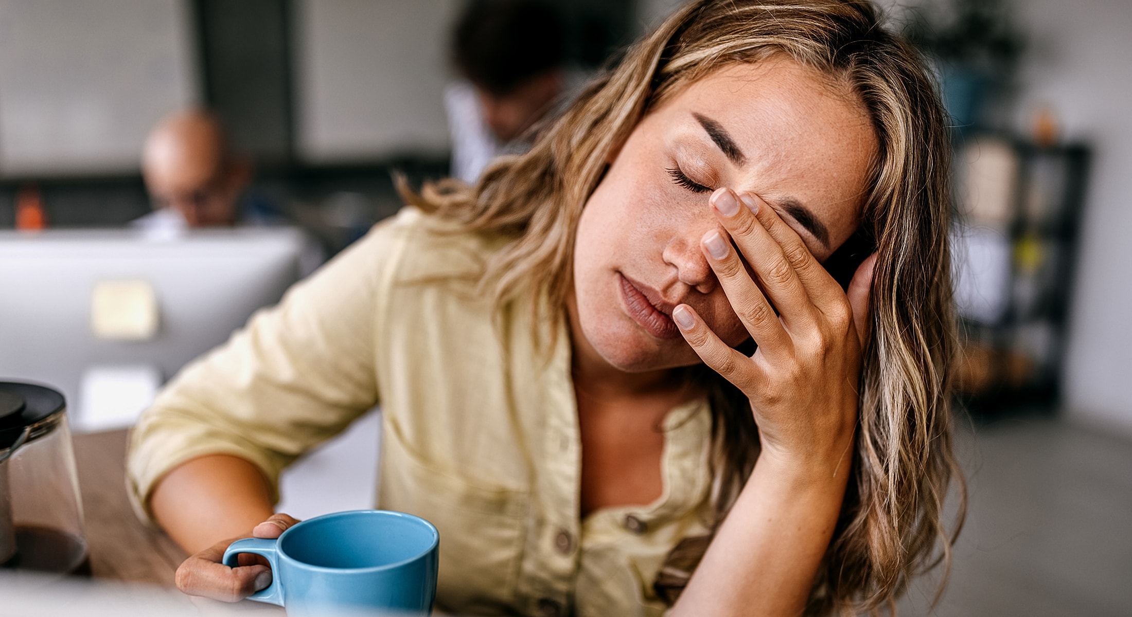 Woman looking stressed while holding a coffee cup.