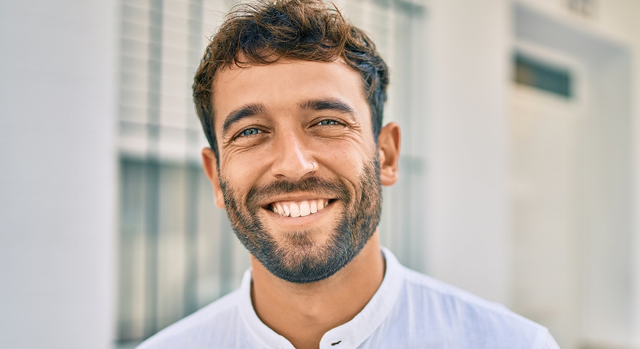 Smiling man with beard wearing a white shirt.